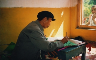 Li Manshan doing paperwork for Hoisting the Pennant ritual, 2003 https://stephenjones.blog/the-film/